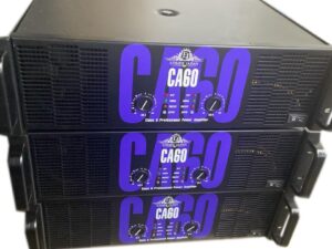 Stack of three Ejimek Japan CA60 professional power amplifiers in black and purple design. Each unit features dual-channel volume knobs, LED signal and protection indicators, efficient cooling vents, and rack-mountable construction. Designed for large-scale sound reinforcement systems and stage audio.