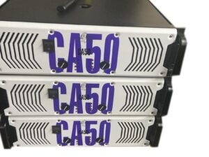Three stacked Ejimek Japan CA50 professional power amplifiers with white front panels and large blue "CA50" lettering. Each amplifier has two black control knobs and a power switch on the left side. The units have black handles on the sides and ventilation patterns on the front panels.