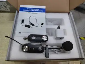 A boxed DN-T3000 UHF wireless headset microphone kit showing the contents: a headset transmitter with volume buttons and boom mic, a receiver with 3.5mm plug, USB charging cable, wall charger, and a user manual titled "UHF Headset Wireless Microphone." The items are neatly organized in foam packaging.