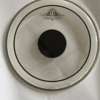 Clear drum head featuring a black center dot and the "EJIMEK JAPAN" logo printed near the top. The drum head is placed on a white surface with visible shadows and light reflections.
