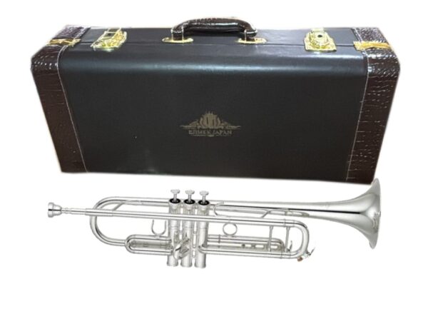A silver Ejimek Japan trumpet placed in front of a black hard carrying case with brown textured edges and gold hardware. The case features the Ejimek Japan logo in the center.